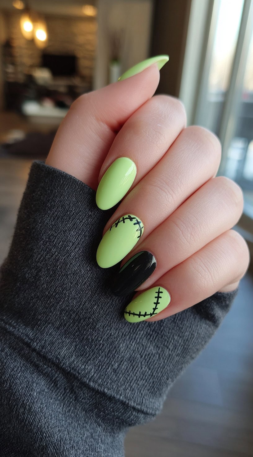Glossy almond-shaped nails in lime green and black with stitched line details.