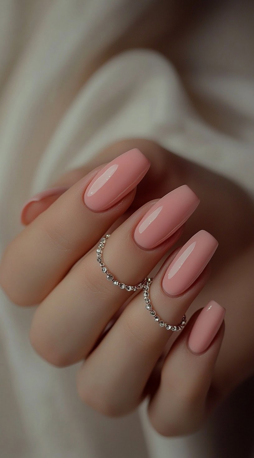 A set of coffin-shaped nails in a soft nude pink shade, featuring a high-gloss finish.