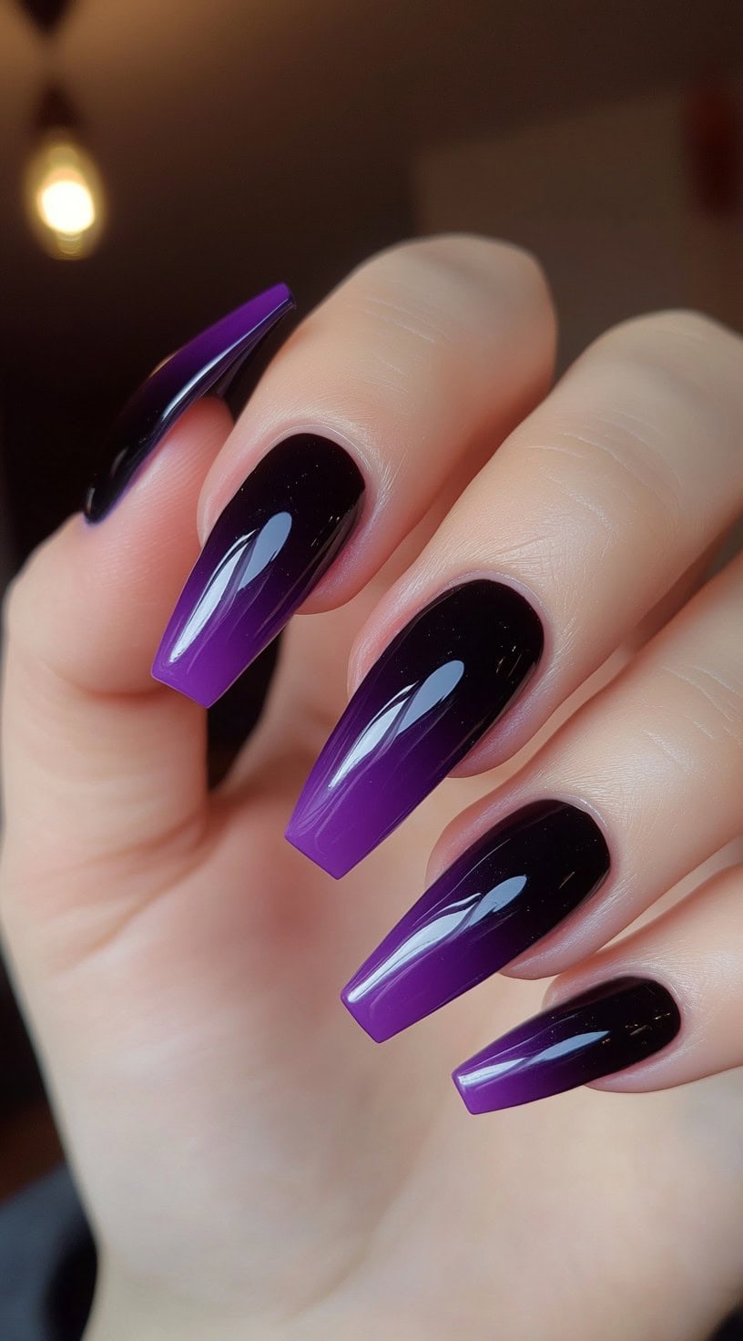 A hand with long coffin-shaped nails featuring a glossy ombre transition from deep purple at the tips to black near the cuticles.