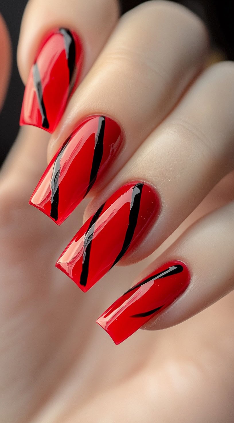 Glossy red square-shaped nails decorated with bold black diagonal stripes.