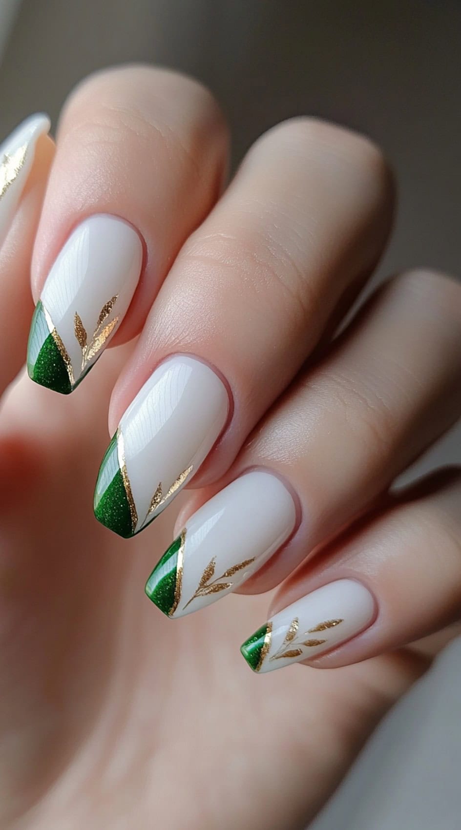 A set of square-shaped nails featuring crisp white polish with deep green French tips, adorned with delicate gold leaf accents.