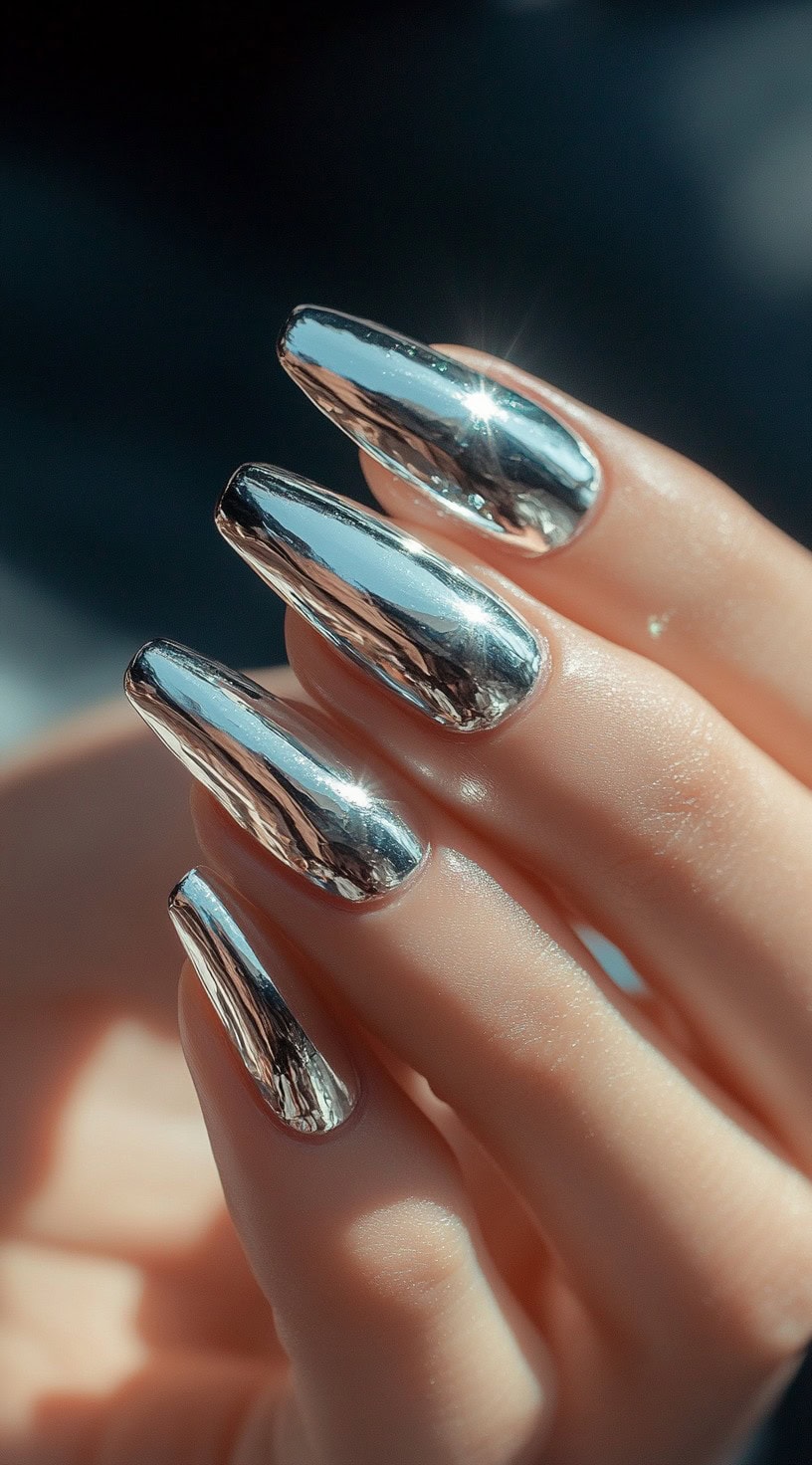 A close-up of coffin-shaped nails with a reflective, high-shine silver chrome finish.