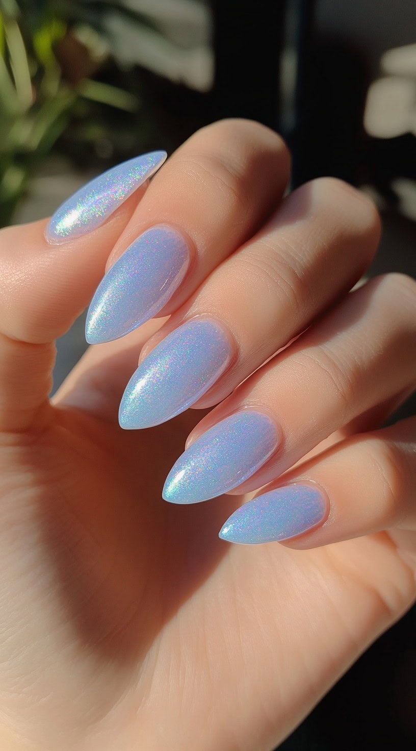 Iridescent pastel blue almond-shaped nails with a holographic shimmer.