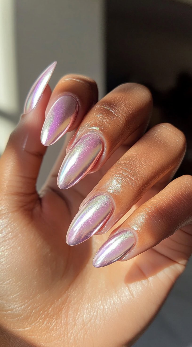 Almond-shaped iridescent pink chrome nails glowing against dark skin in sunlight.
