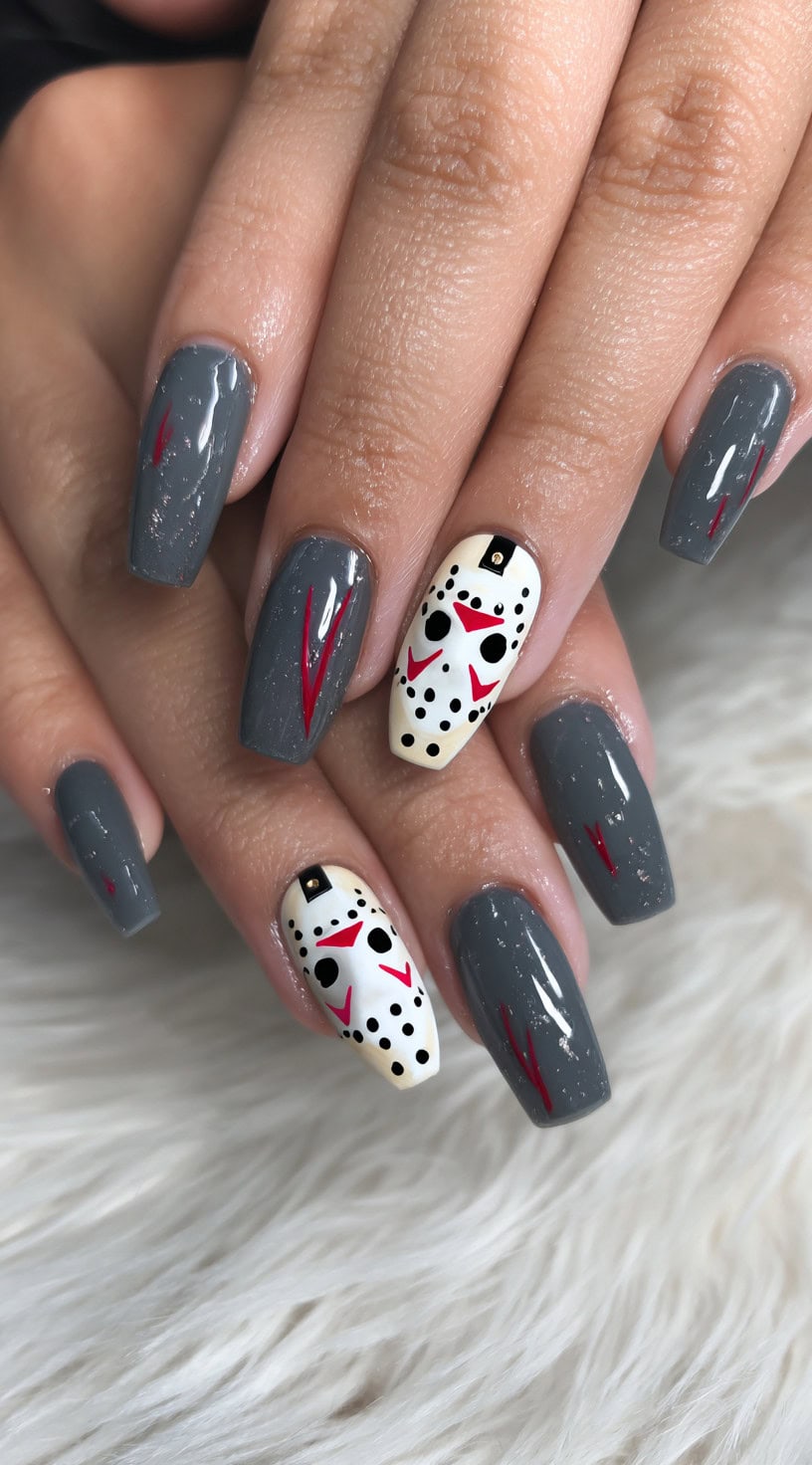 Square-shaped nails in glossy grey with red scratch marks and two white accent nails featuring Jason Voorhees' iconic hockey mask.
