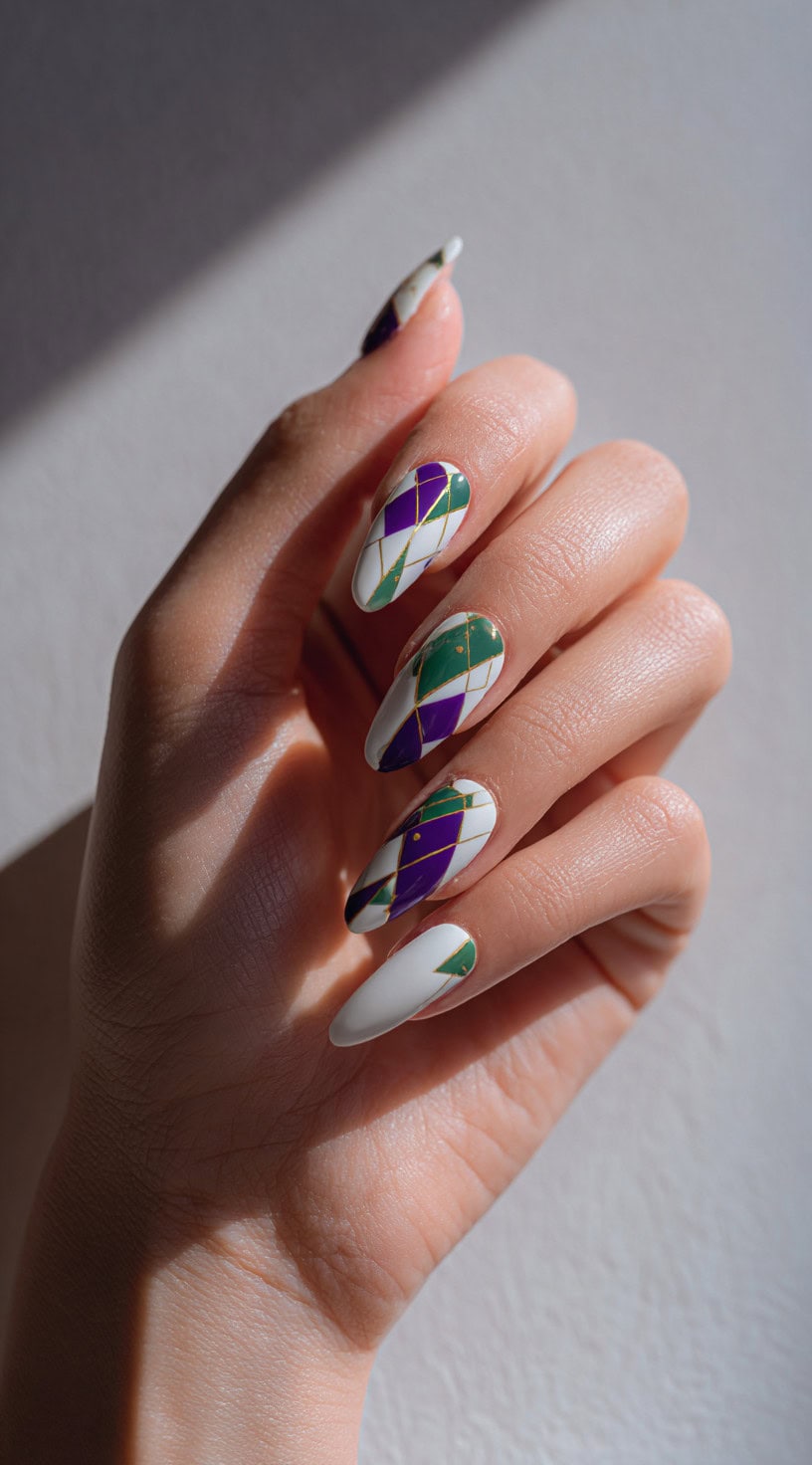 Almond nails painted in white, purple, and green diamond patterns separated with thin metallic gold lines.