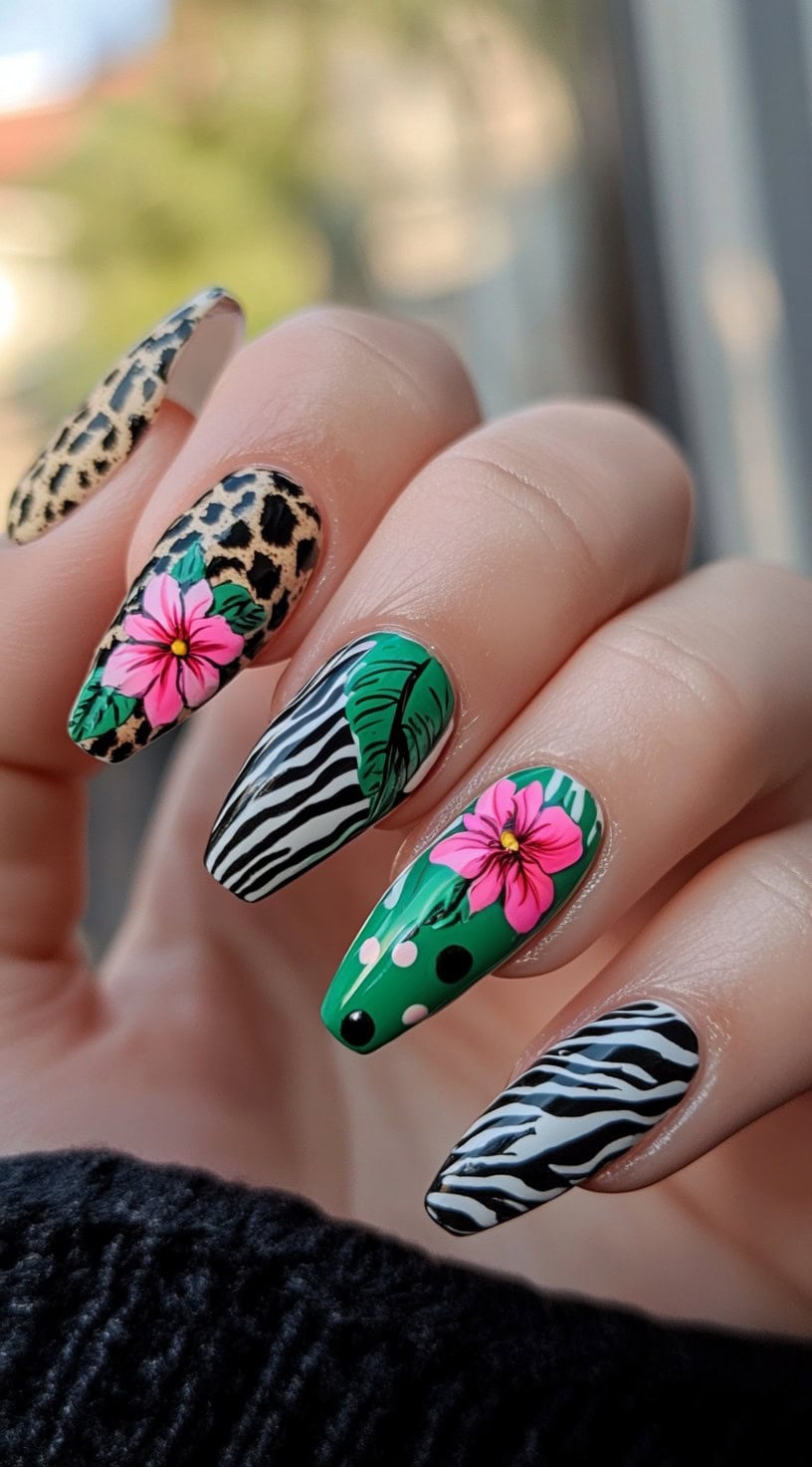 Stiletto-shaped nails with animal print patterns, tropical leaf accents, and vibrant pink flowers.