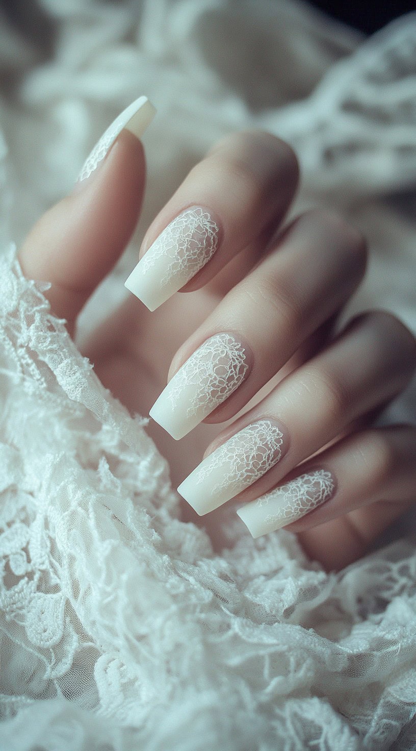 A set of long square-shaped wedding nails in matte white, featuring delicate lace-like embossed patterns on the surface.