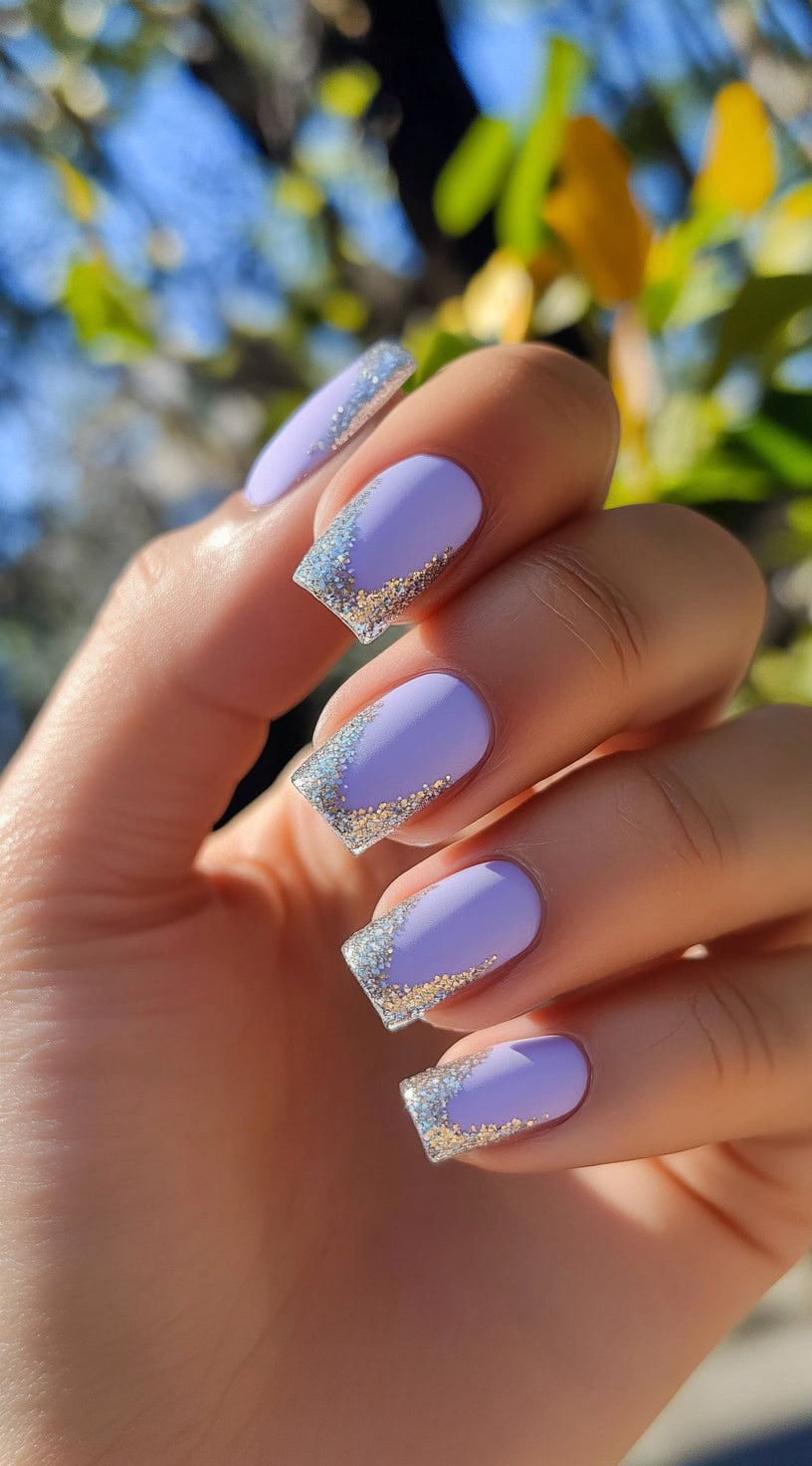 Hand with square-shaped lavender nails featuring glittery French tips.