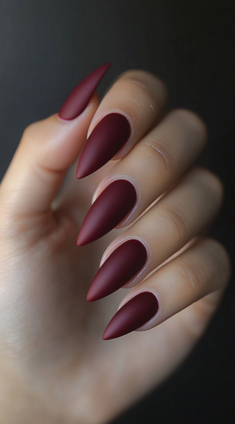 Matte deep burgundy stiletto-shaped nails with a velvety finish.