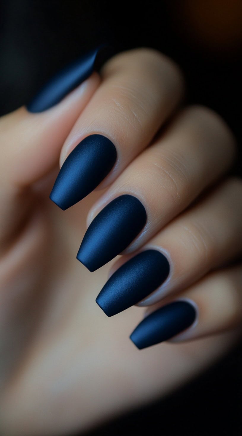 Almond-shaped nails painted in a deep midnight blue with a matte finish.