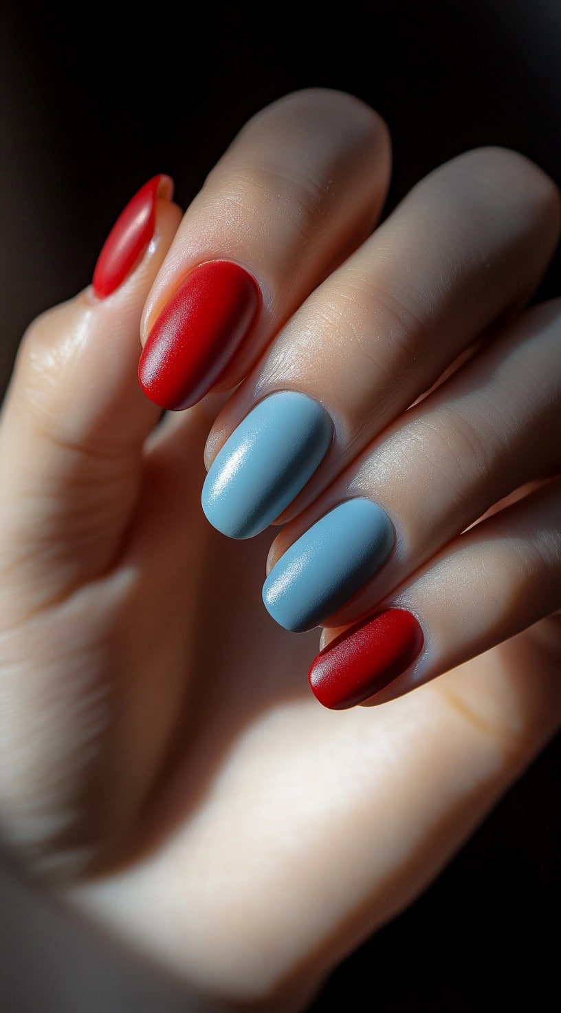 A hand with alternating matte red and muted blue nails, creating a modern and elegant contrast.