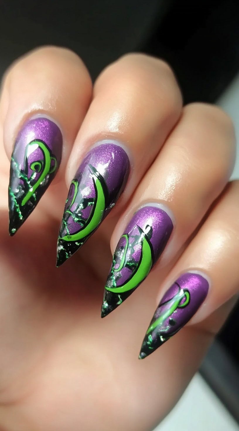 Hand with metallic purple stiletto nails decorated with green flame-like swirls and dark tip accents.