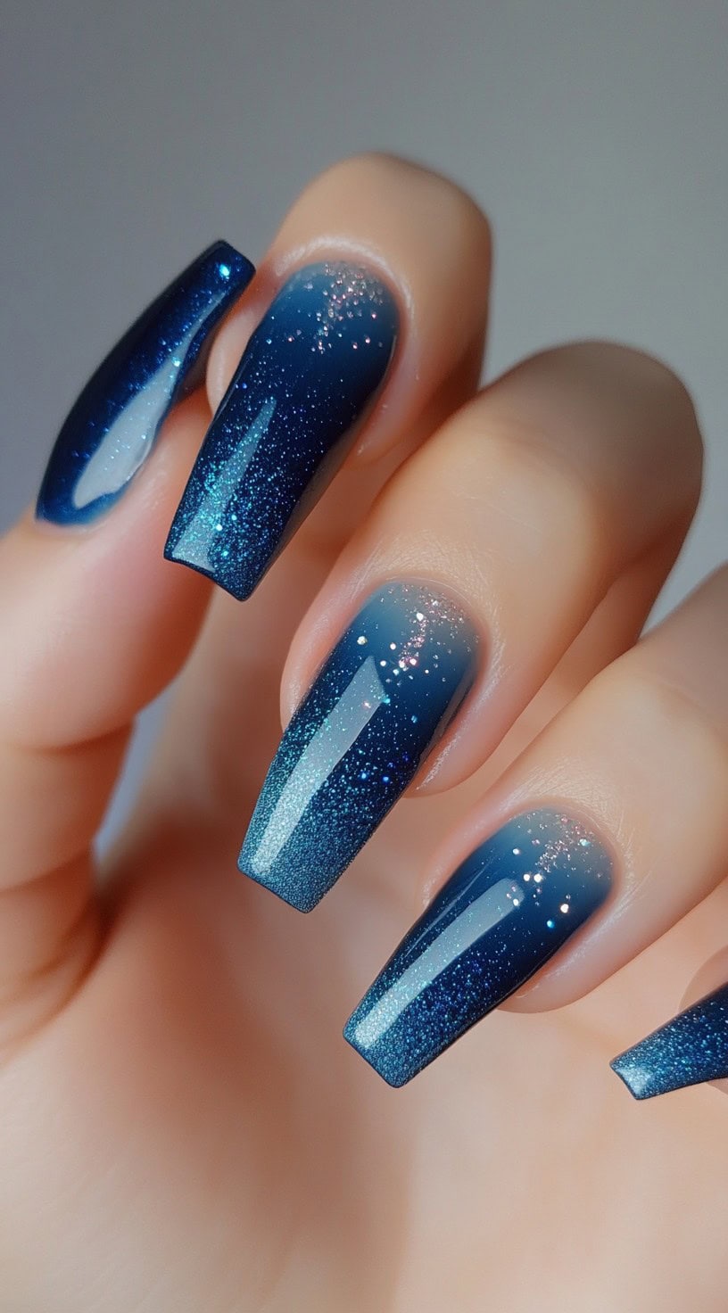 Deep midnight blue ombre nails with a glitter gradient fading toward the tips.