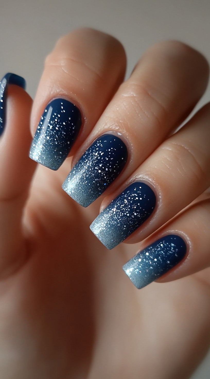 Square-shaped nails with a deep navy base fading into silver glitter tips.