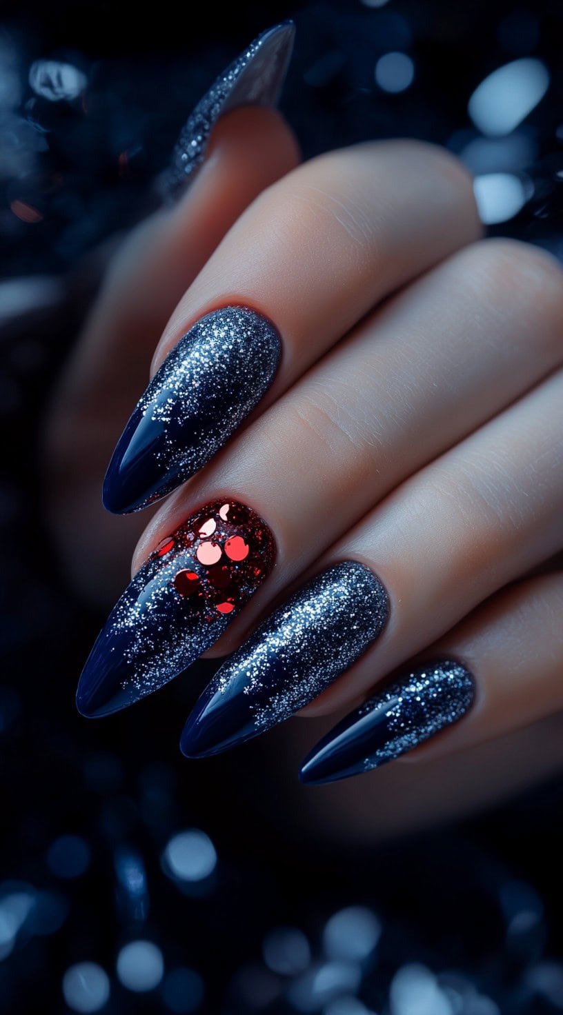 Long almond-shaped nails with a dark navy base, silver glitter gradient, and a red glitter accent nail.