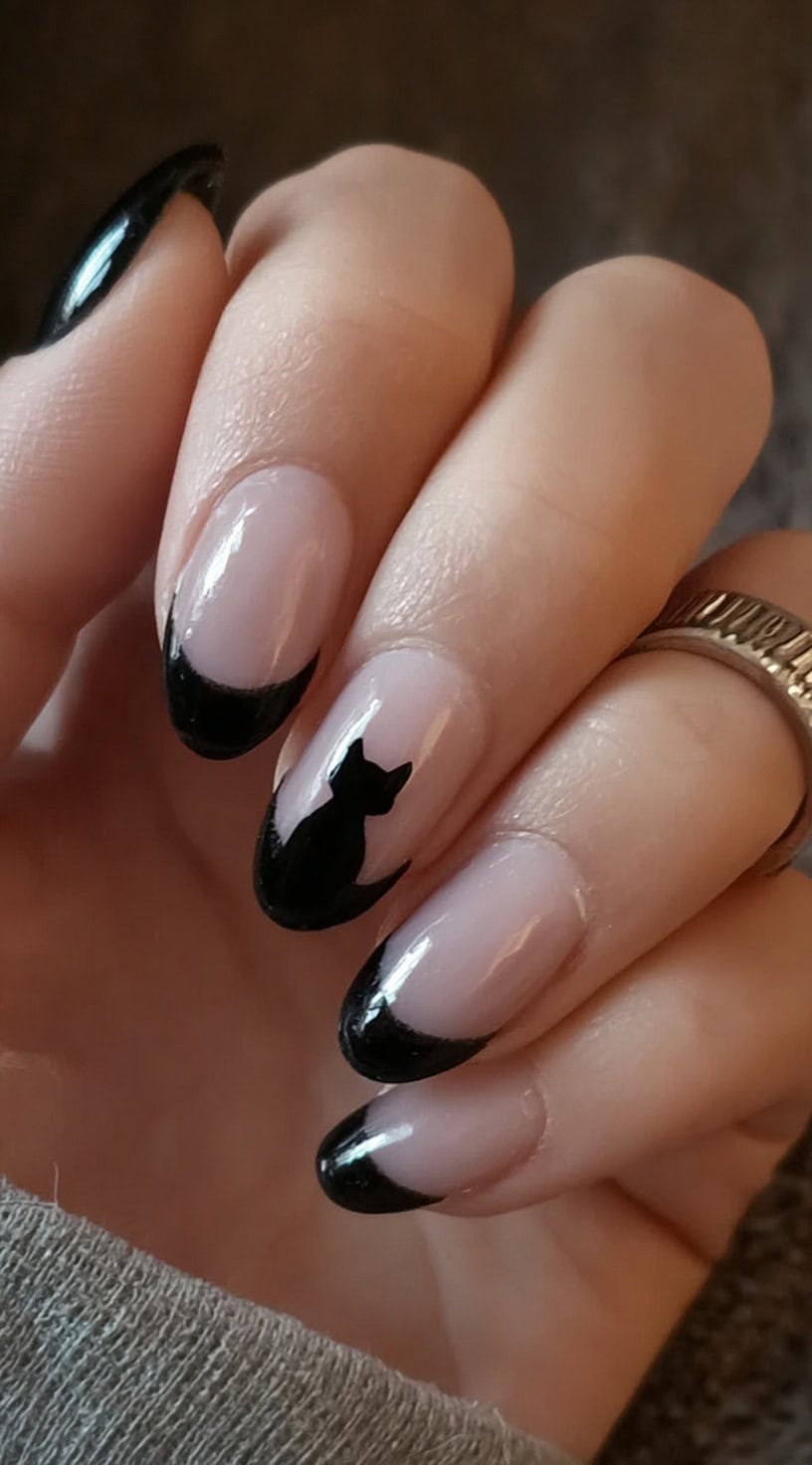 Almond-shaped nails with sheer pink bases and black French tips, with one nail featuring a sleek black cat silhouette at the base.