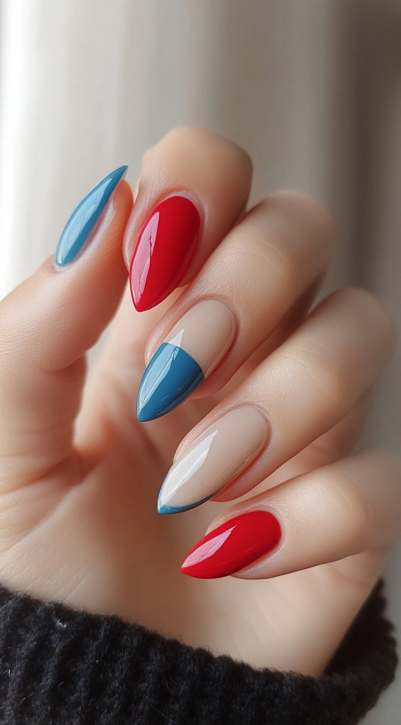 Almond-shaped nails featuring a modern French tip design in bold red and soft blue over a sheer base.