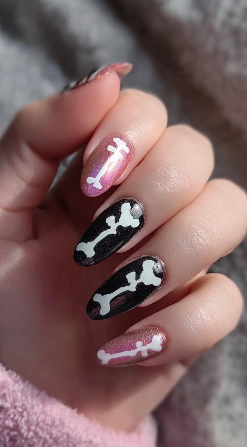 Five almond-shaped nails with a mix of shimmering rose and glossy black polish, each decorated with white bone designs.