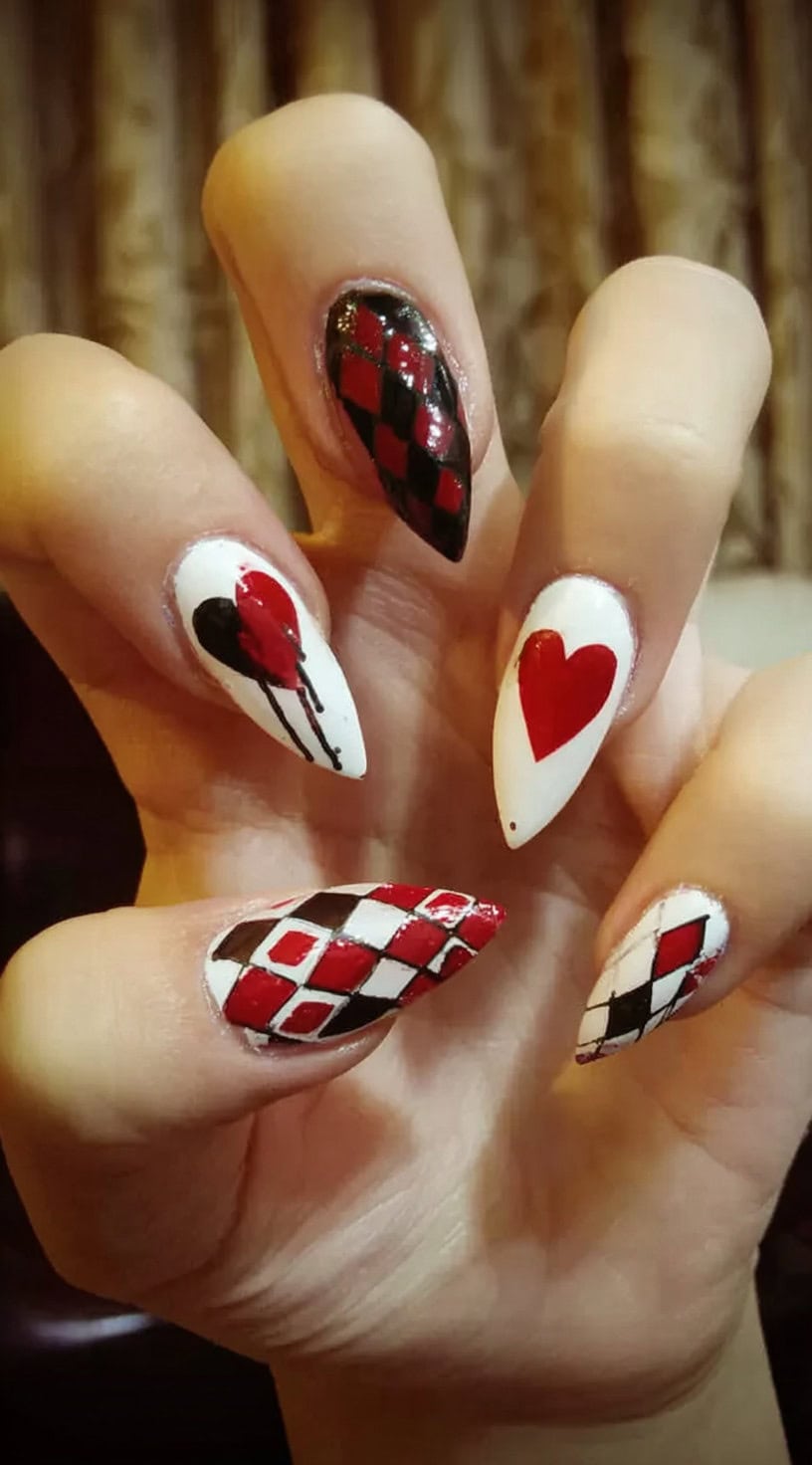 Almond nails featuring hand-painted argyle, dripping hearts, and red-and-black graphic hearts on a white base.