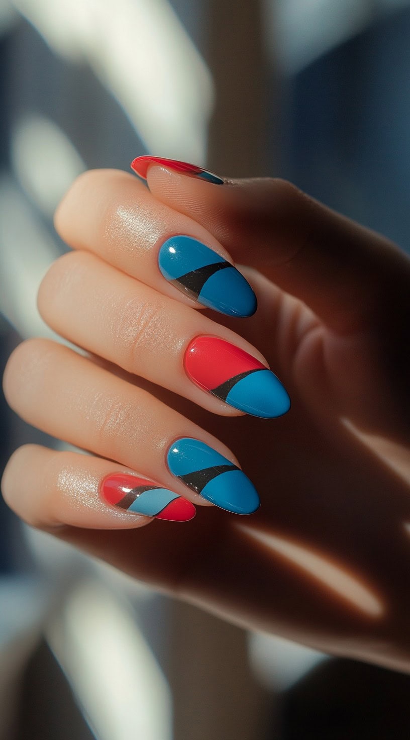A close-up of nails with a striking geometric pattern featuring bold red, blue, and black curves in a glossy finish.