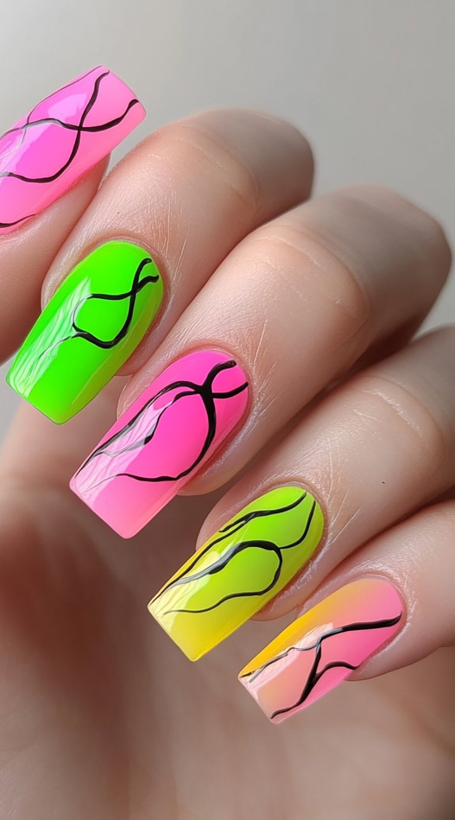 Square nails painted in neon pink, green, yellow, and peach with black squiggle line accents.