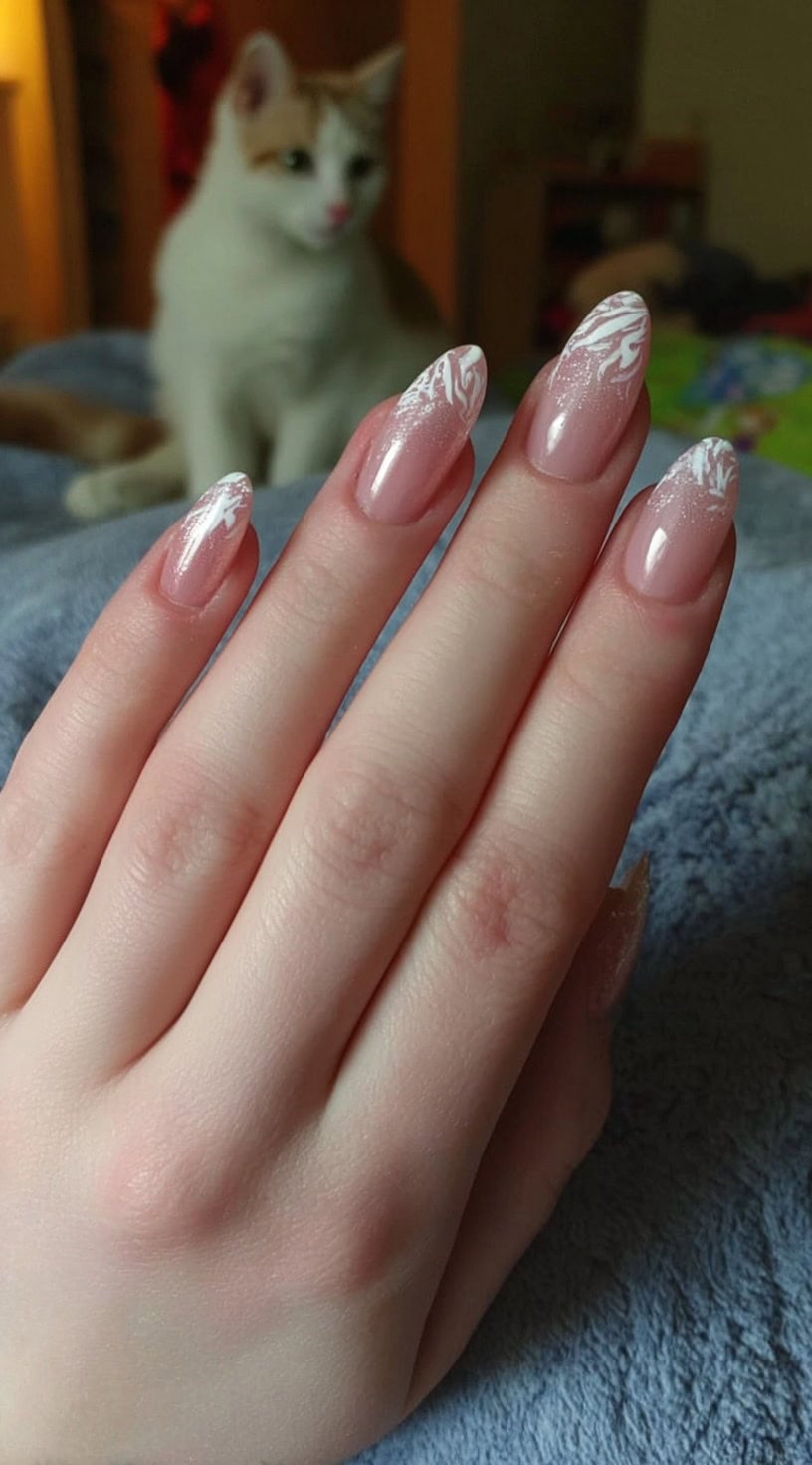 Almond-shaped nails with a nude base and wispy, feathered white French tips featuring subtle marbling.
