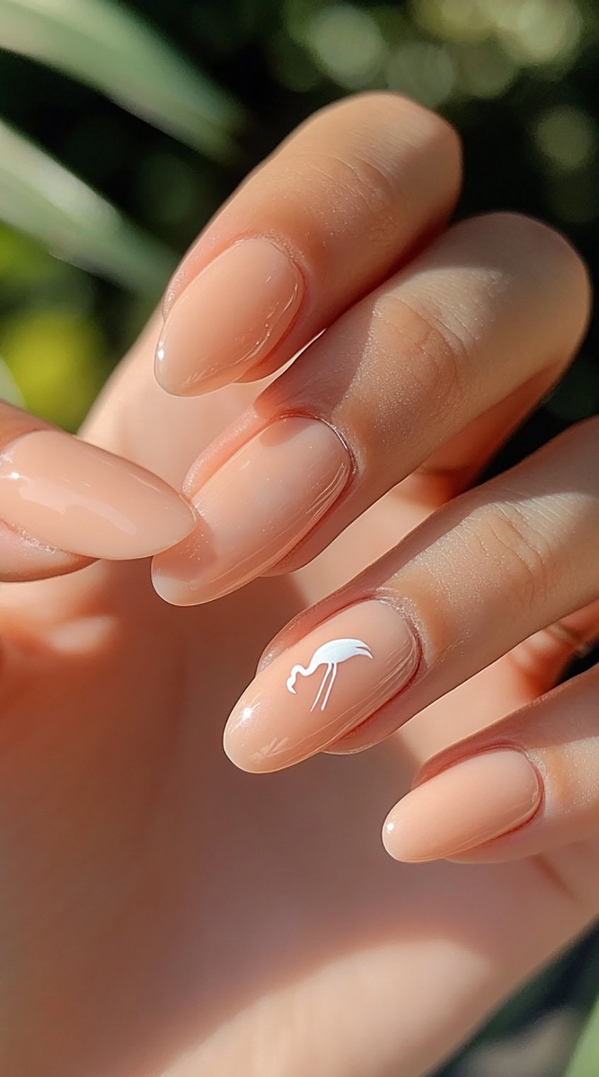 Hand with almond-shaped nude nails and a white flamingo design on one nail.