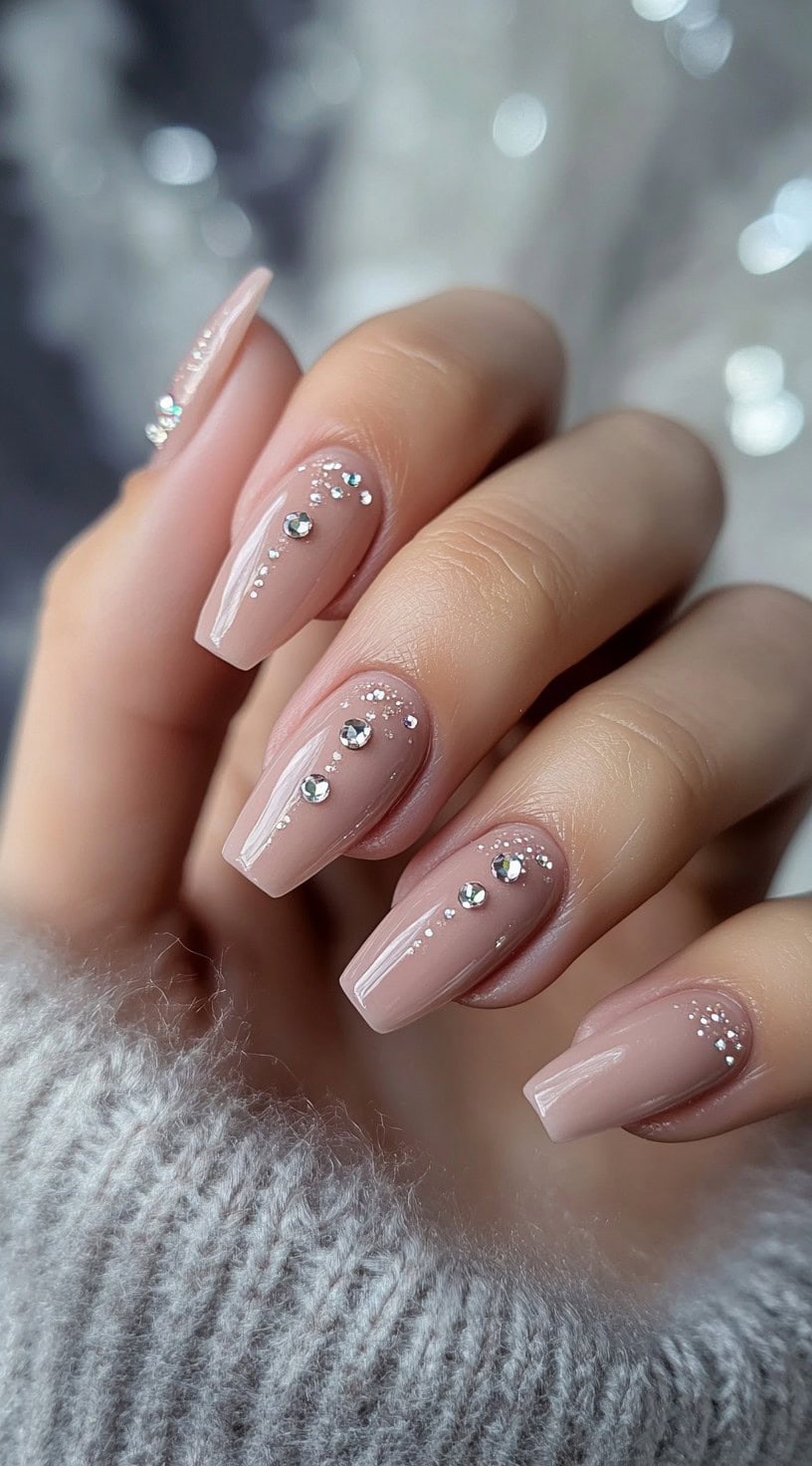 A set of long, coffin-shaped nude pink nails adorned with delicate rhinestones and fine dot accents.