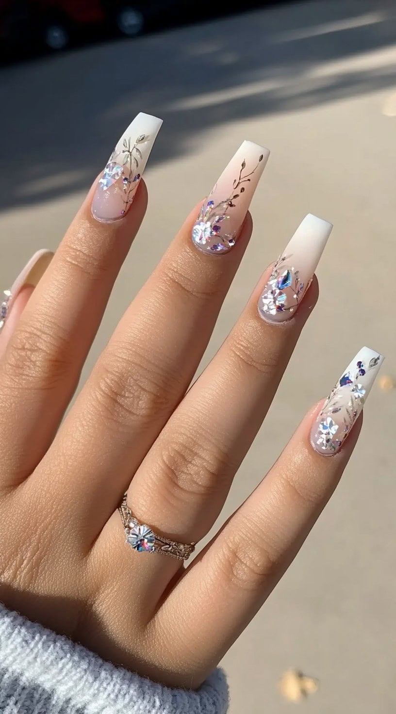 Five ombre French coffin nails transitioning from pink to white, adorned with rhinestones and silver branch-like patterns.