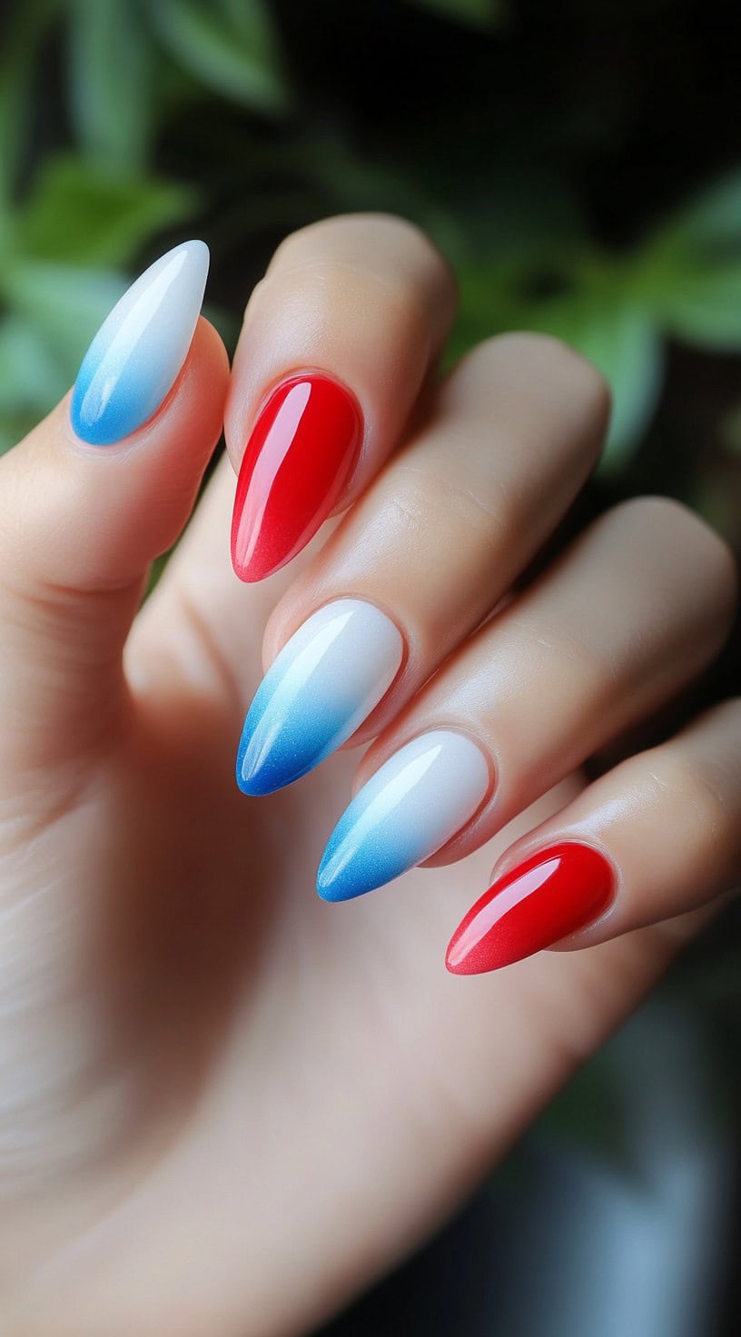 Almond-shaped nails with an ombre fade transitioning from white to blue, paired with bold red accent nails.