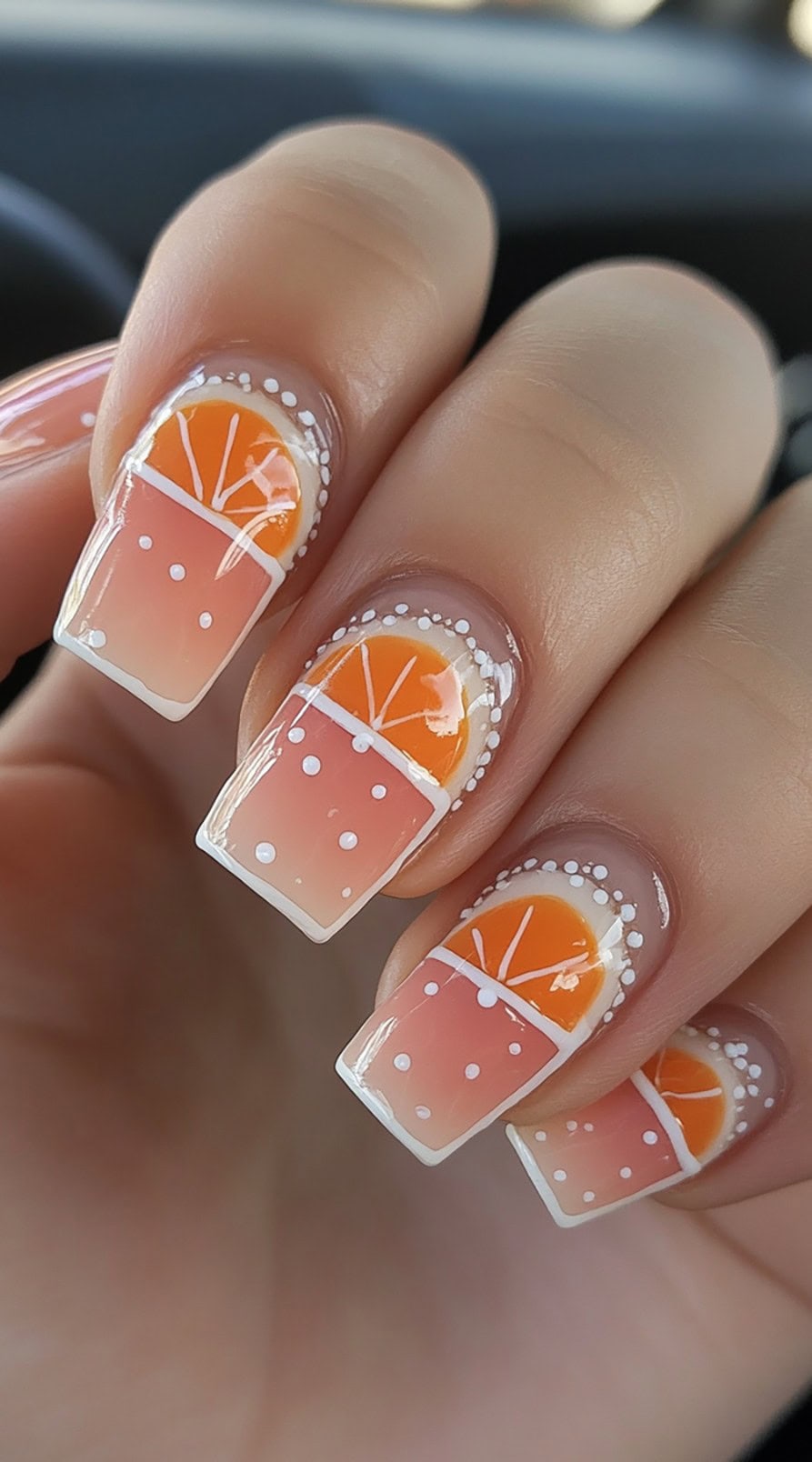 Square-shaped nails with orange slice designs on the tips and white dot accents framing the cuticle.