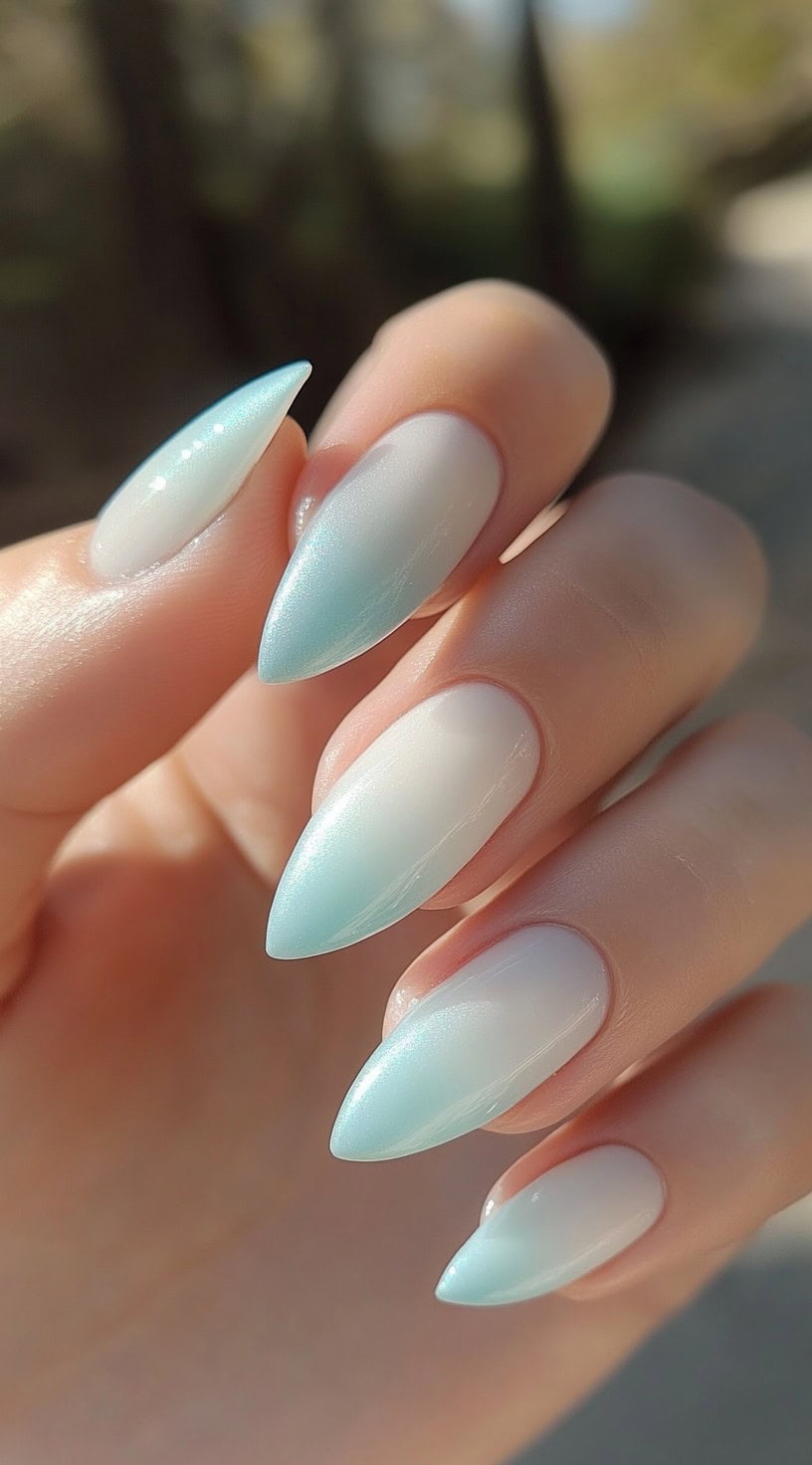 Long almond-shaped nails with a pastel blue to white ombre effect, giving a soft and airy look.