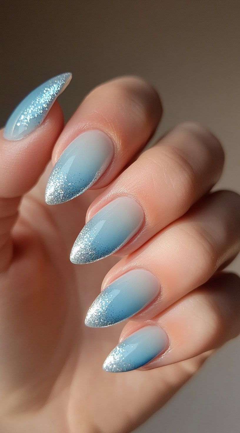 Almond nails with a soft baby blue ombre and glittery silver French tips.