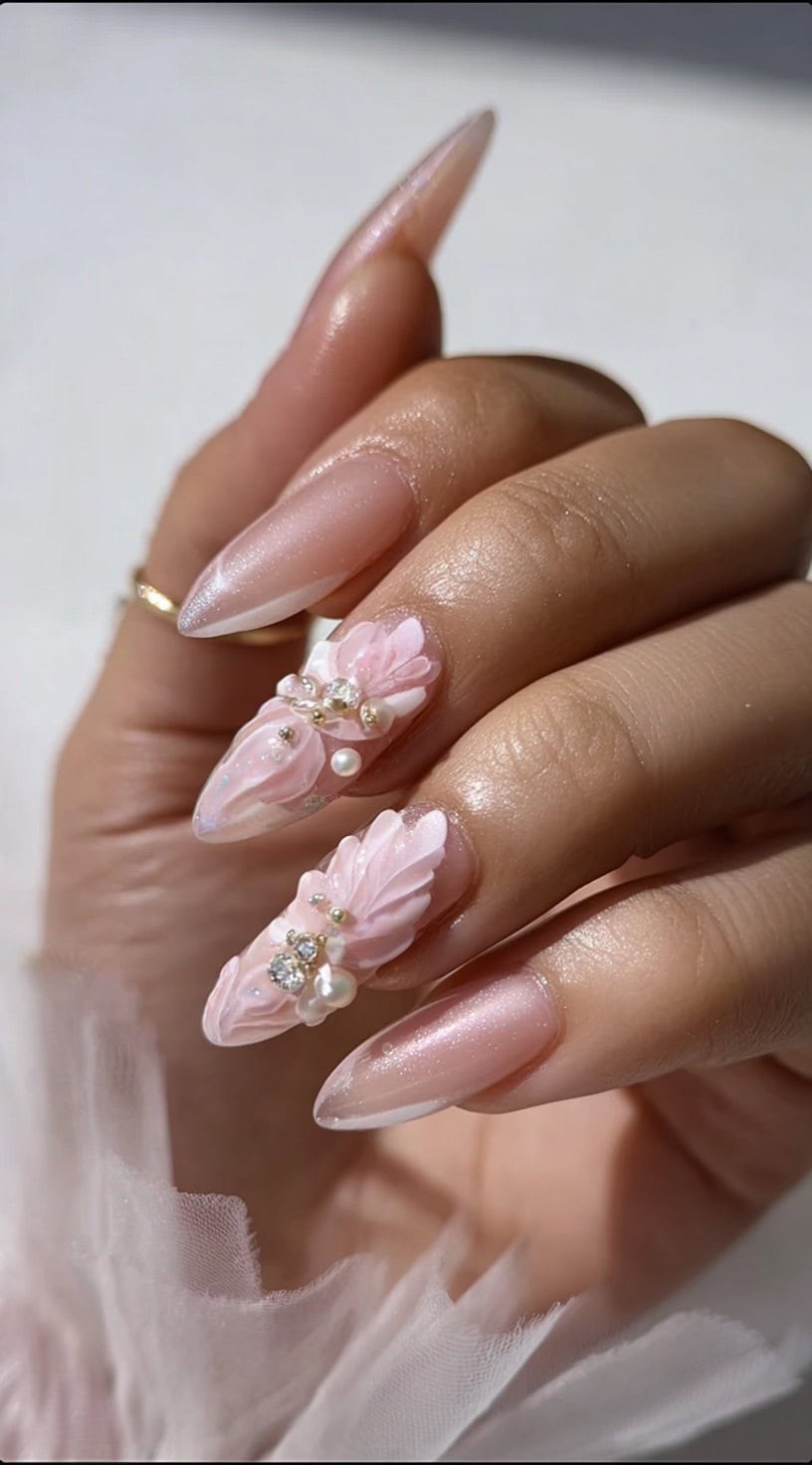 Almond-shaped nails in pearl pink with accent fingers covered in sculpted pink petals, pearls, and tiny crystals.