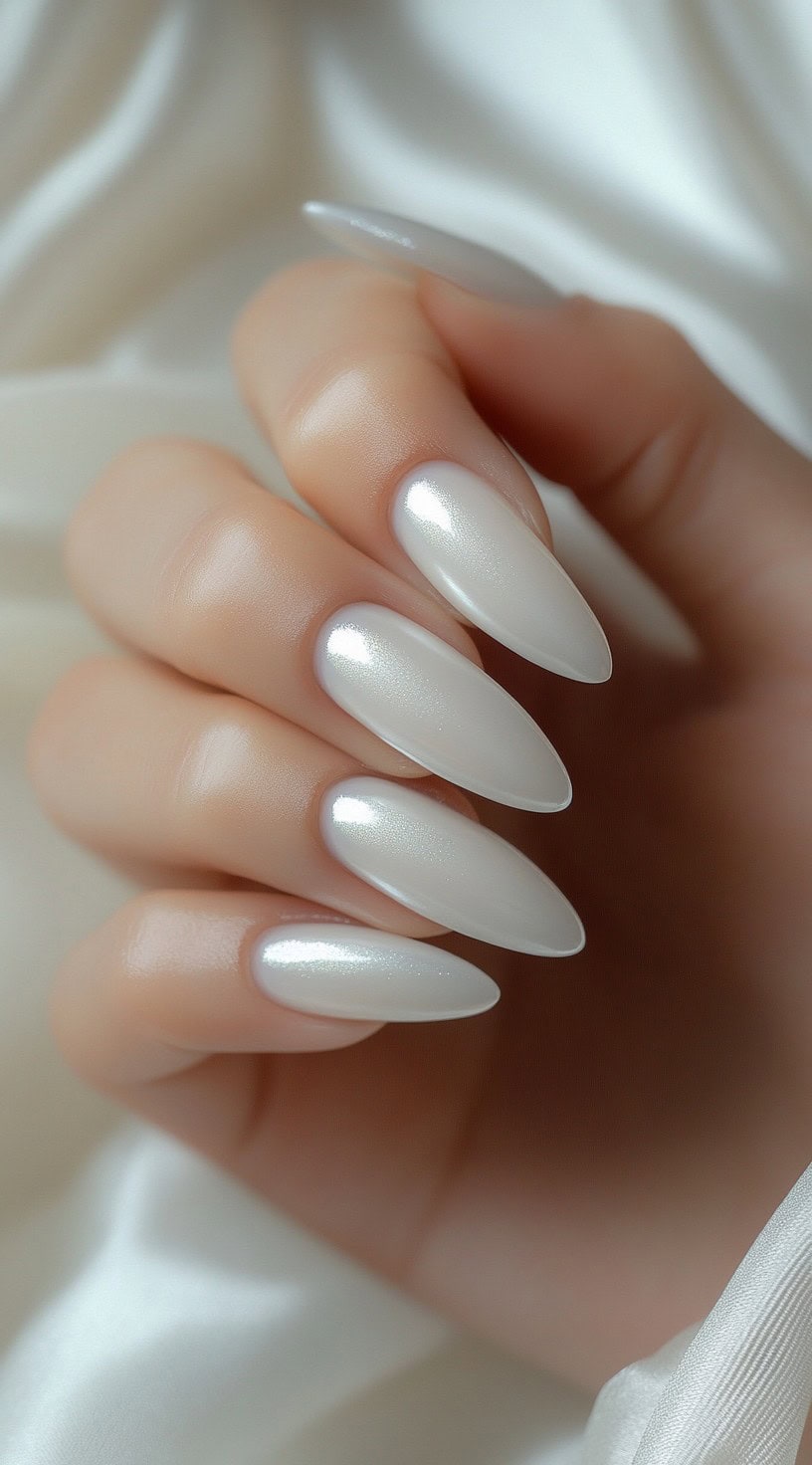 Elegant almond-shaped nails coated in a pearlescent white polish with a subtle shimmer.