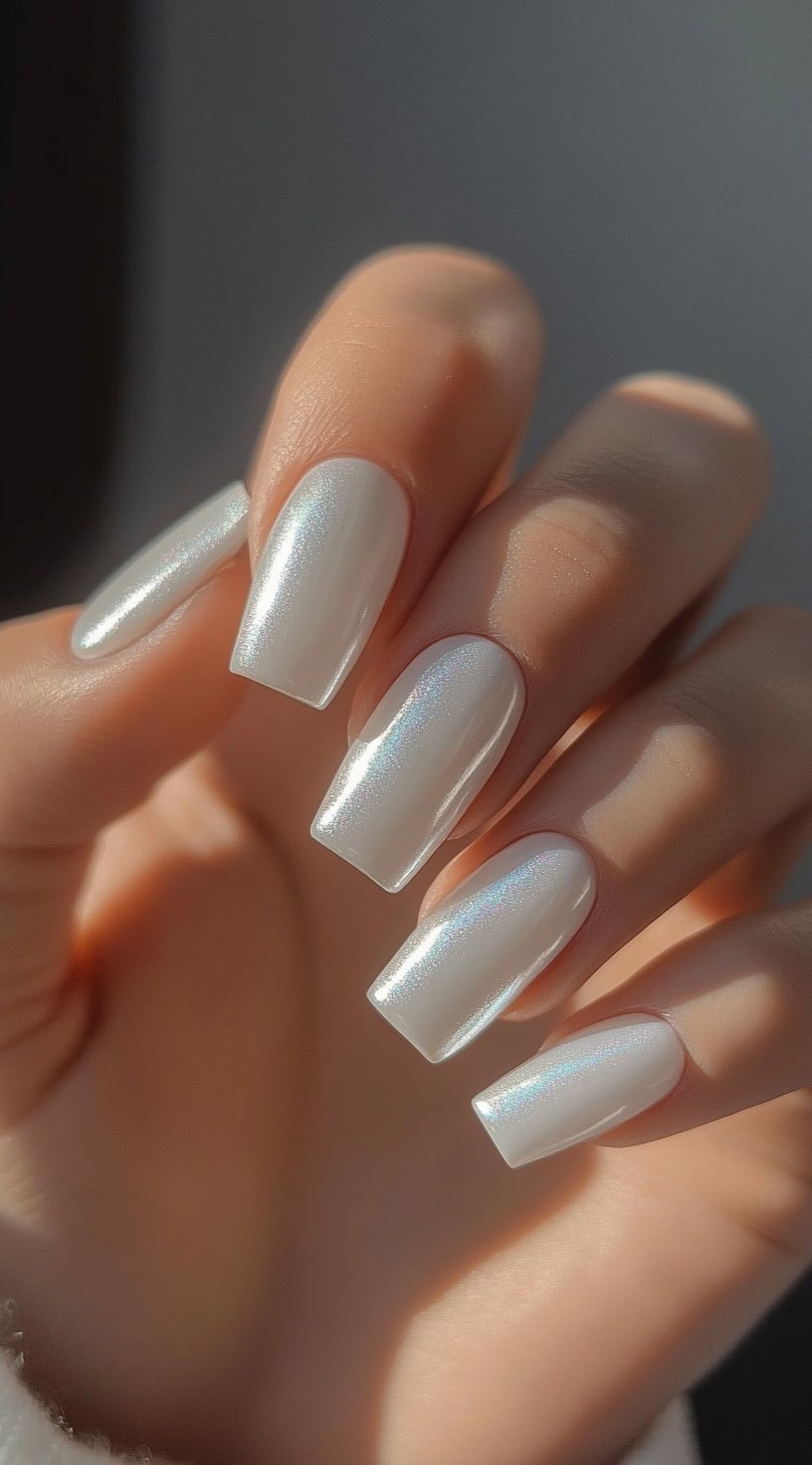 A set of white square nails with a pearlescent chrome finish that reflects light beautifully.