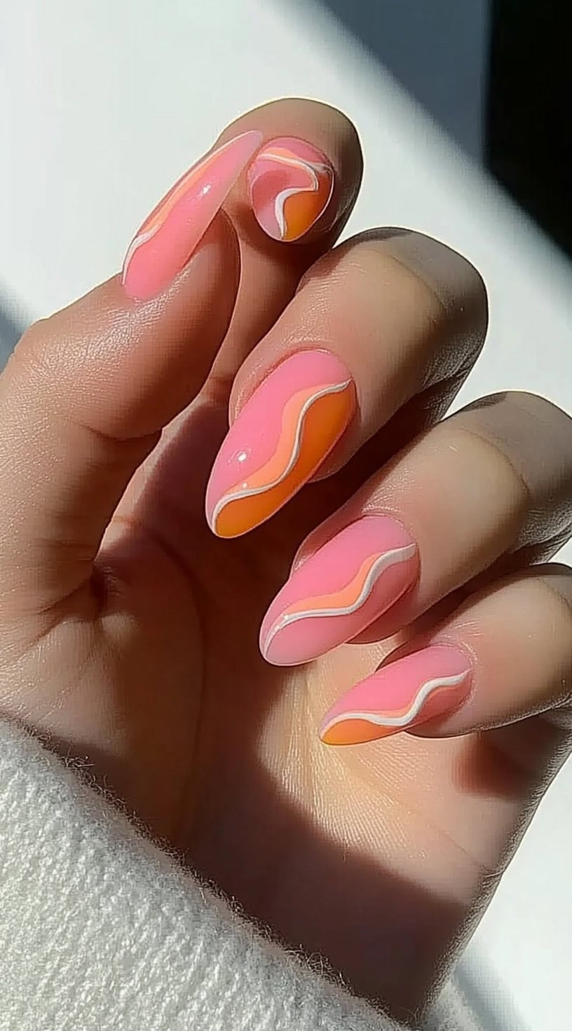 Almond-shaped nails painted with pink and orange base tones, detailed with wavy white and peachy lines.