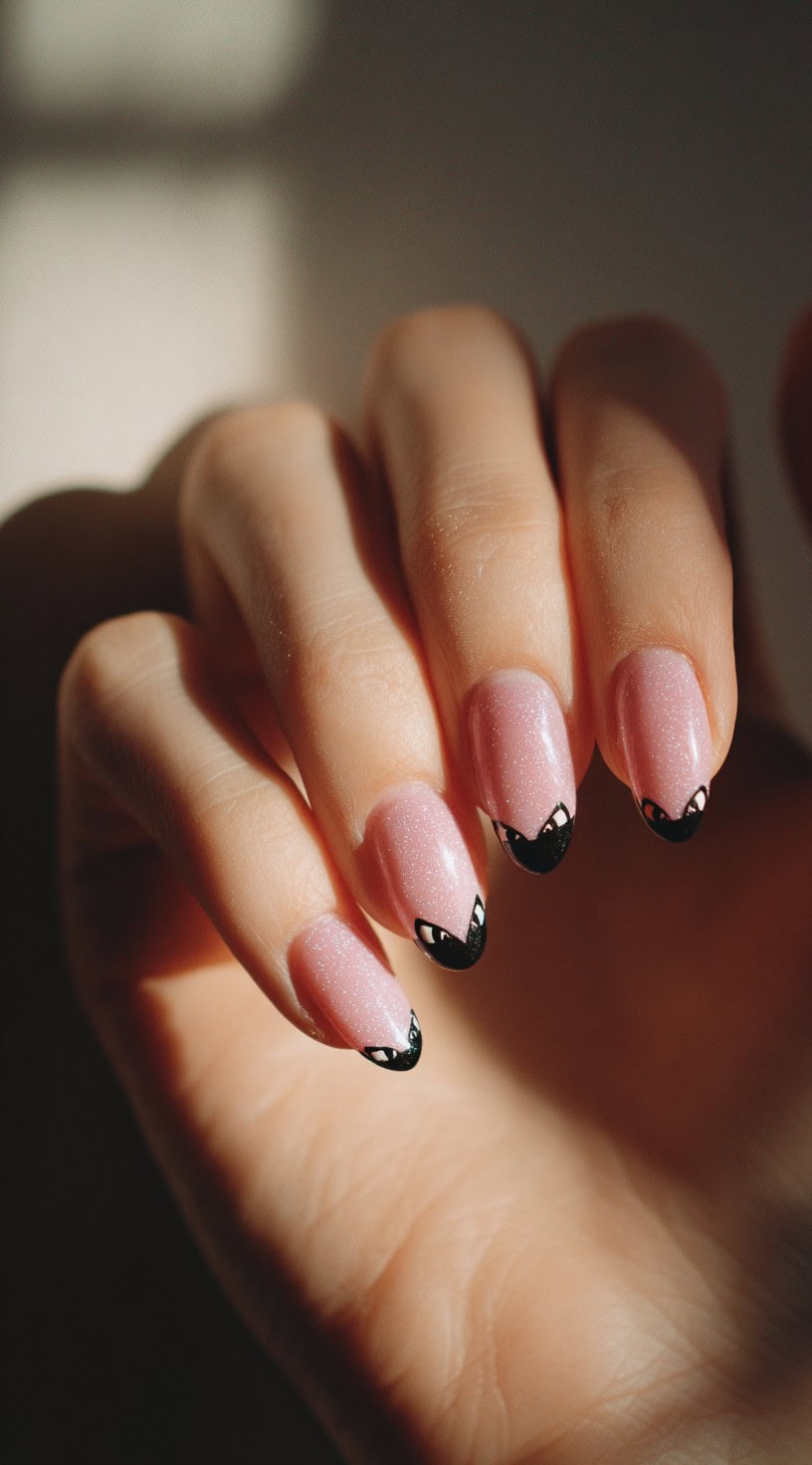 Hand with almond pink nails featuring black French tips shaped like sneaky cat eyes.