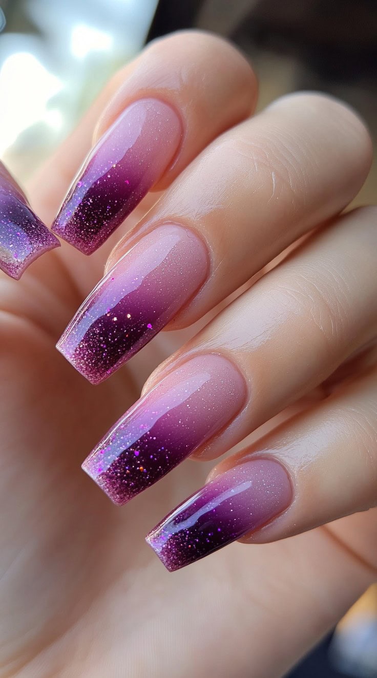 Square nails with a smooth fade from pale pink to deep plum, accented by shimmering purple and silver glitter.