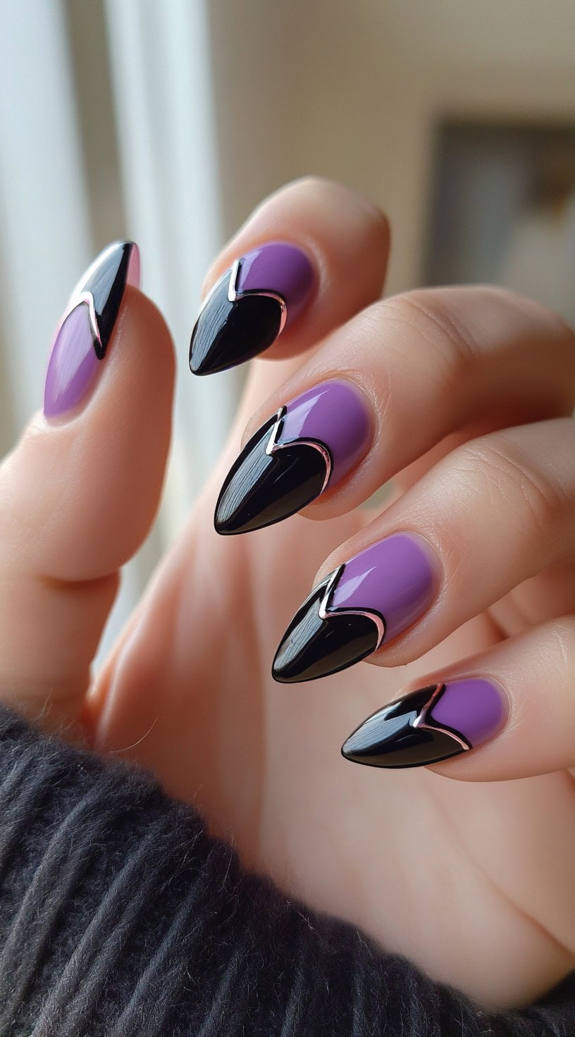 A set of almond-shaped nails painted purple with black chevron tips outlined in silver chrome.