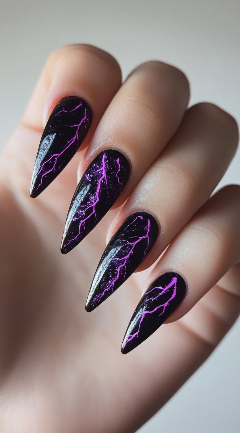 Stiletto nails painted black with bright purple lightning bolt art and subtle glitter.