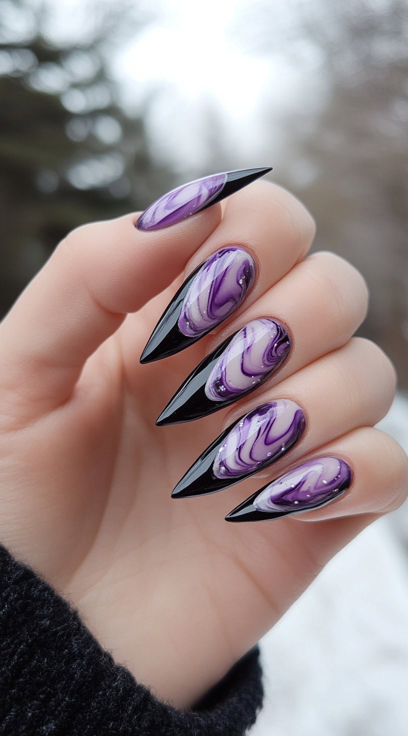 A hand with long almond-shaped nails in purple marble and black, featuring pointed French tips with a glossy finish.