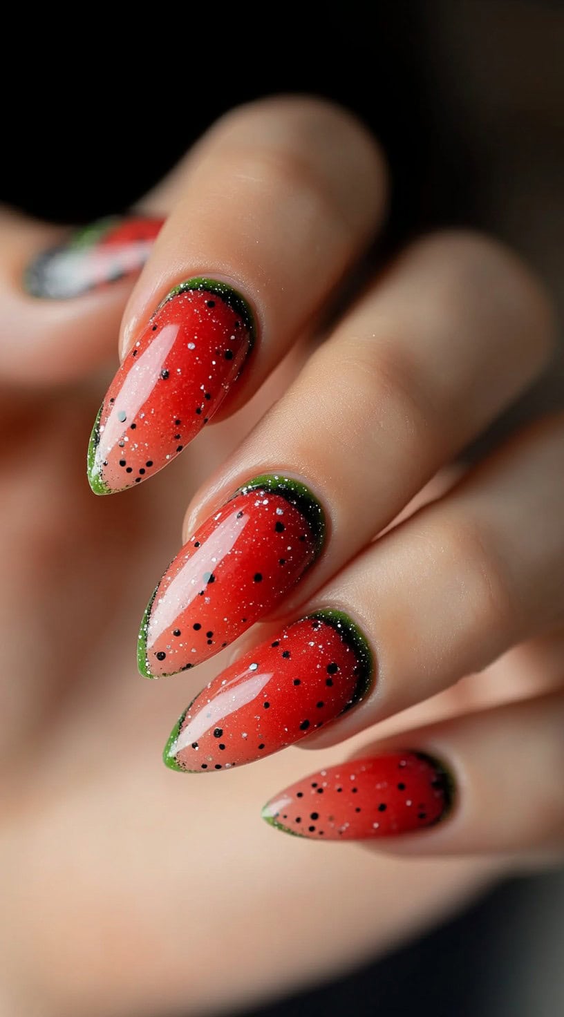 Almond-shaped nails with a glossy red-to-green ombre that resembles real watermelon slices with black seeds.