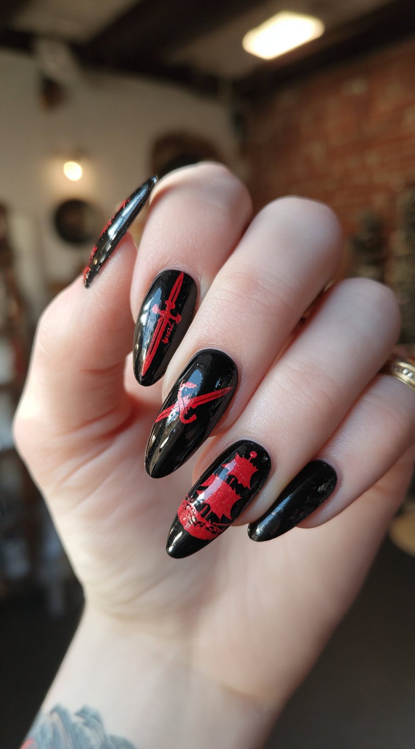 Glossy black almond nails are decorated with bold red sword, pirate skull, and ship designs for a dramatic contrast.