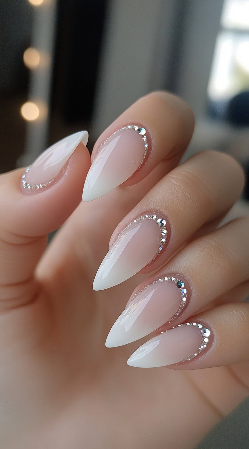 Stiletto-shaped French nails with rhinestone accents along the cuticle line.
