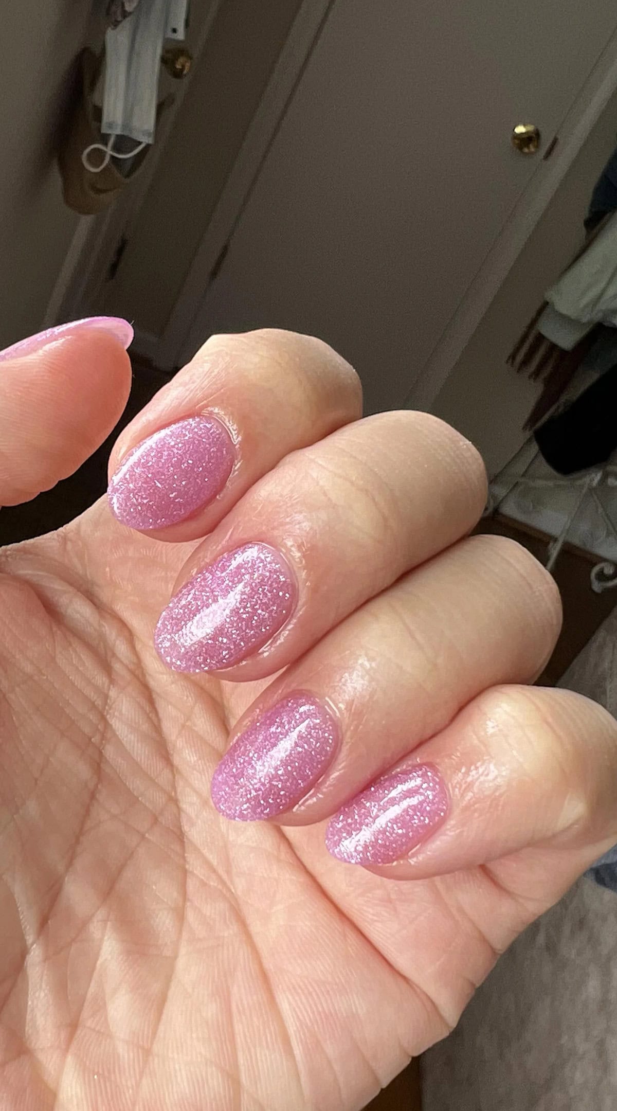 Short round nails with soft pink glitter polish, a flattering choice for short nail beds that adds subtle sparkle and enhances natural nail shape.