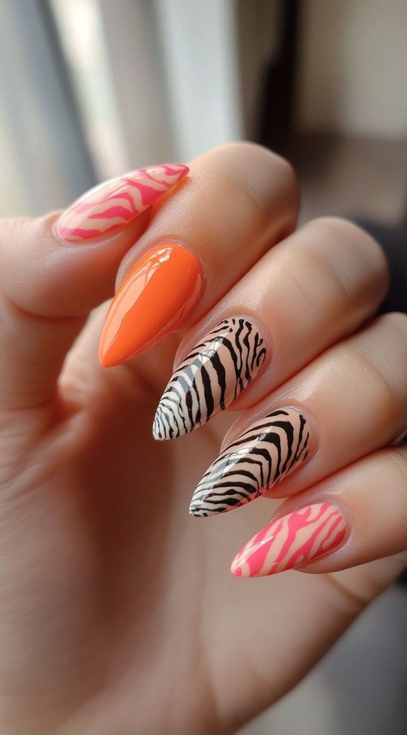 Almond nails with a mix of bright orange, pink zebra, and black-and-white zebra print designs.
