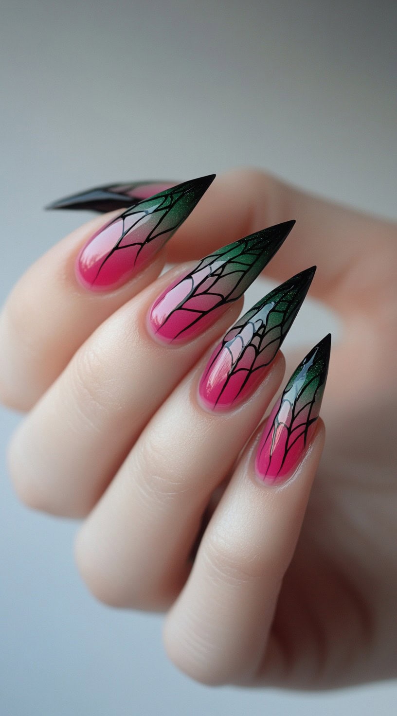 A hand with sharp stiletto nails in a pink to green ombre with intricate black web-like nail art.