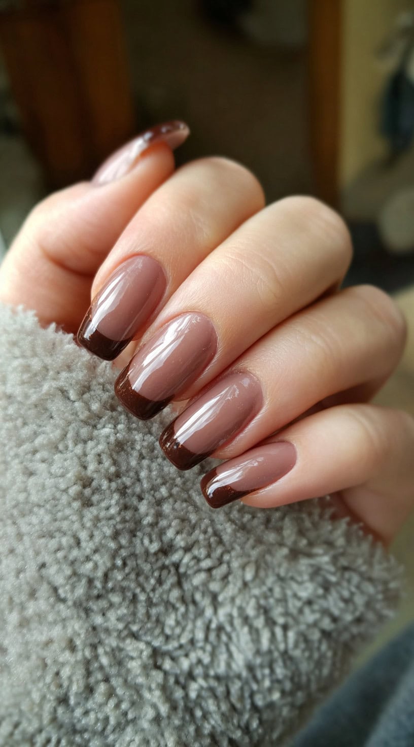 Medium-length nails with a sheer nude base and rich chocolate brown French tips.
